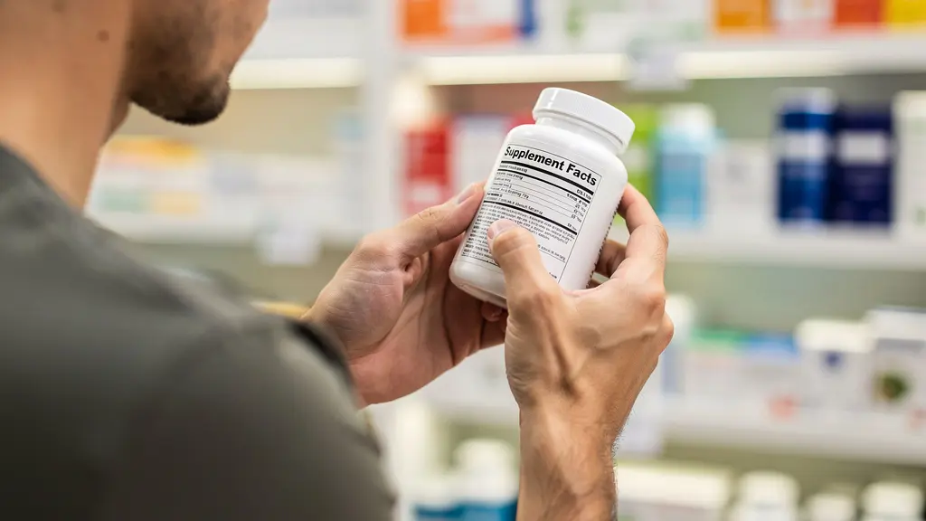 Customer checking vitamin supplement label quality indicators in pharmacy setting